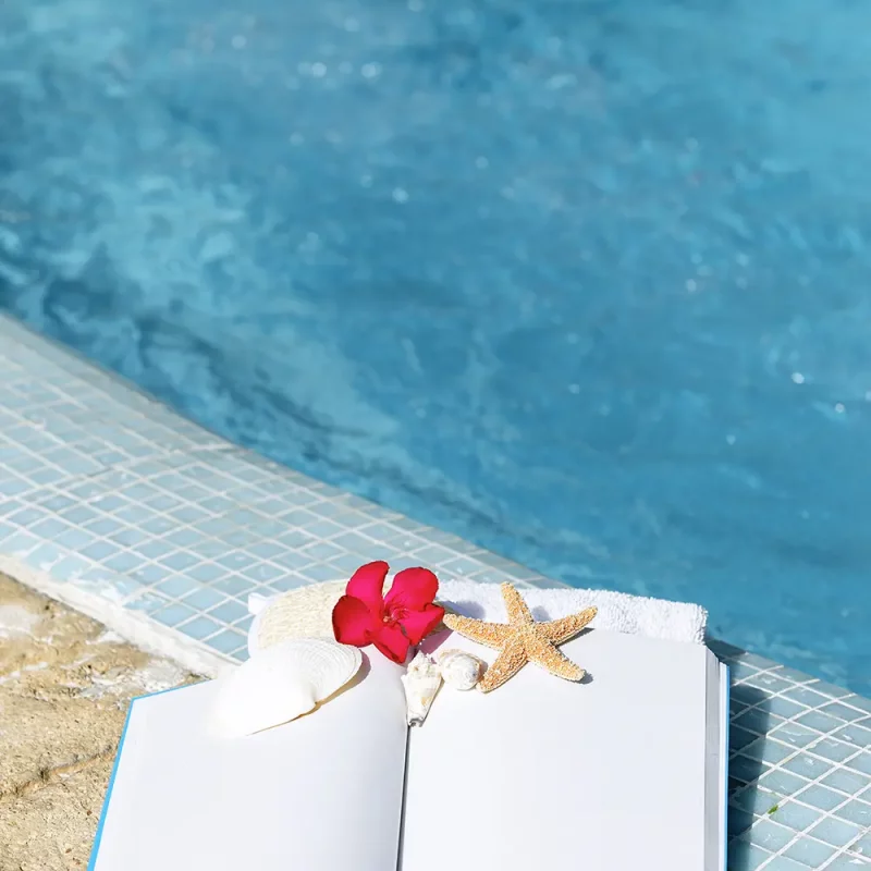 View of swimming pool with open book on edge